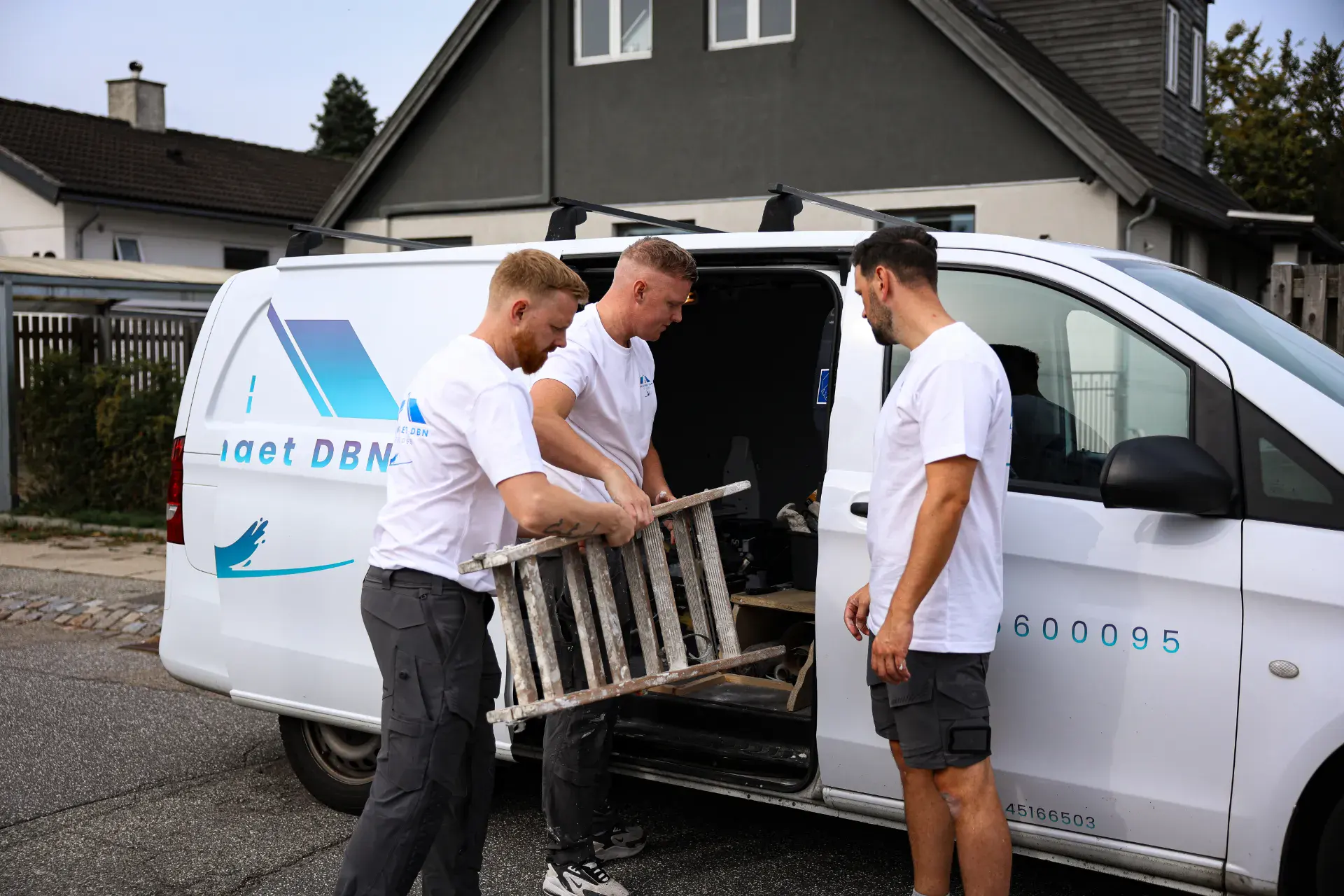 Malerteam arbejder med udstyr ved firmabilen.